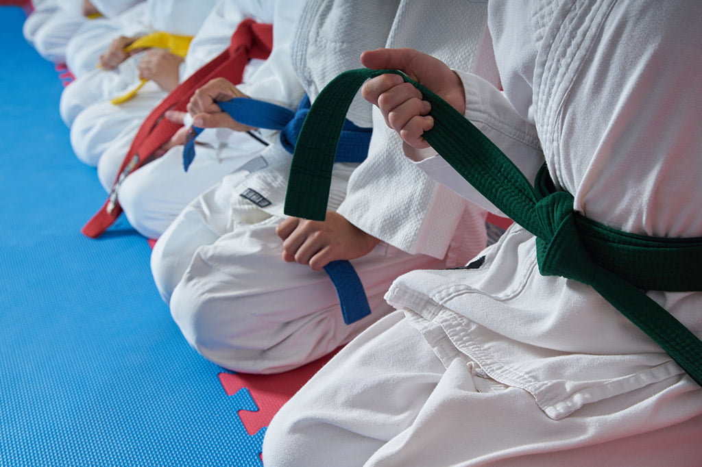 kids sitting holding karate belts