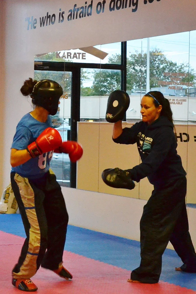 Tammy Bernardo holding mits for a student as they punch