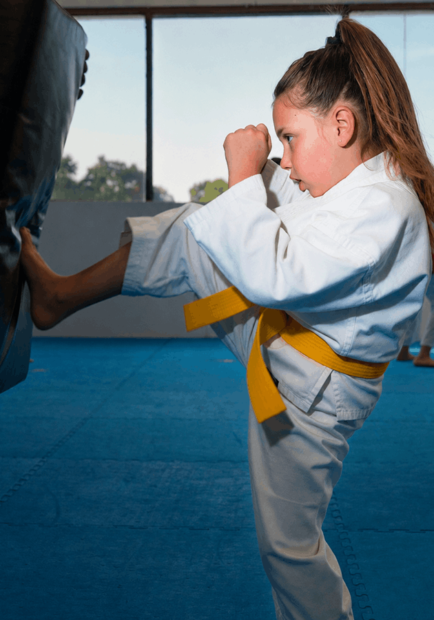 girl-kicking-bag-sm Girl kicking bag at Bernardo karate in a yellow belt karate gi